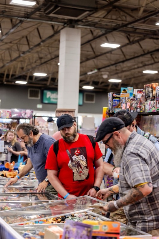 Collectors leaning over glass cases filled with small vintage toys and collectibles