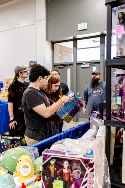 A young collector carefully reading the back of a boxed toy while others browse nearby