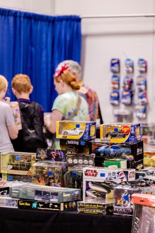A young girl with a red bow browsing Star Wars and boxed toys with her family